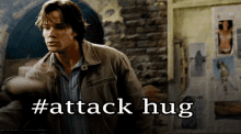 a man in a jacket is standing in front of a wall with the words #attack hug written on it