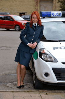 a woman stands next to a police car with the word policija on the top