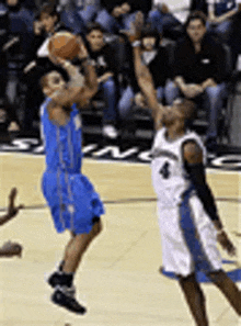 two basketball players are playing a game of basketball on a court .