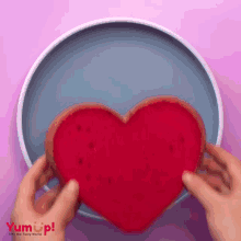 a person is holding a heart shaped cookie on a blue plate