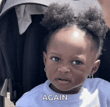 a little girl is sitting in a stroller and making a funny face with the word again written above her