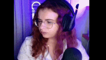 a woman wearing glasses and headphones is sitting in front of a microphone in a room .