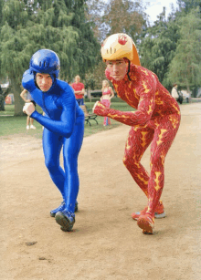 a man in a blue suit is standing next to a man in a red suit with flames on it