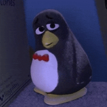 a stuffed penguin wearing a bow tie is sitting on a table .