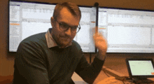 a man sitting at a desk in front of two computer monitors with one of them displaying a foreign language on it