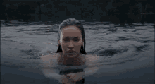 a woman is swimming in a body of water without a shirt on .