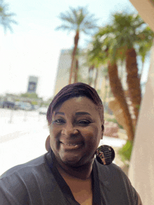 a woman stands in front of a palm tree wearing a black shirt