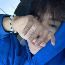 a person wearing a blue hoodie covering their face with their hands