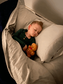 a young boy sleeping with a teddy bear that says ' gingerbread ' on it