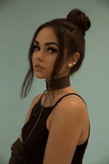 a woman wearing a choker and a bun looks to the side