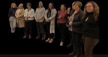 a group of women standing in a line with one wearing a yellow ribbon