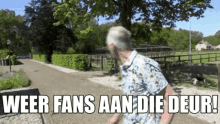 a man is walking down a dirt road with the words weer fans aan die deur written on it .