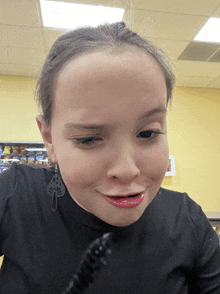 a girl wearing a black shirt and earrings making a face