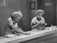 two women are standing next to each other at a counter in a kitchen .