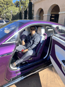 a man is sitting in the driver 's seat of a purple sports car