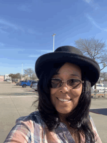 a woman wearing a black hat and sunglasses smiles for the camera