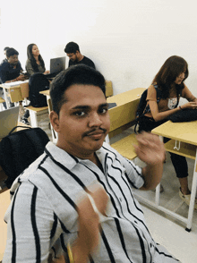 a man in a striped shirt sits in a classroom