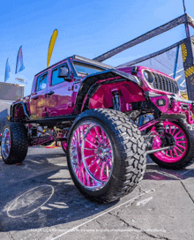 a pink jeep with pink wheels is parked on the sidewalk