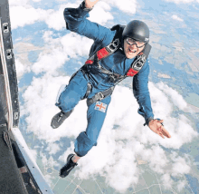 a man in a blue suit with a british flag on his chest is jumping in the air