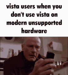 a man with glasses is looking at a cell phone with the words vista users when you do n't use vista on modern unsupported hardware