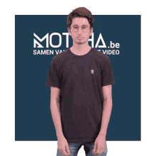 a man wearing a black shirt is standing in front of a blue background that says motia.be