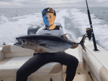 a man holding a large fish on a boat with a yamaha motor behind him