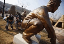 a group of people are squatting down in front of a statue of a man .