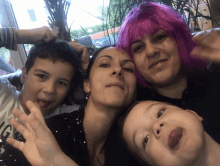 a woman wearing a pink wig is standing next to two children