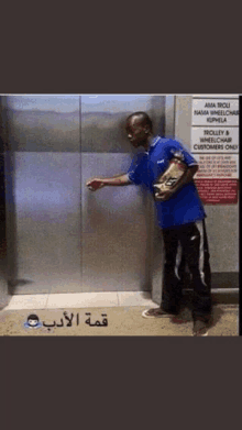 a man in a blue shirt stands in front of an elevator