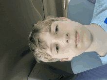 a young boy sits in the back seat of a car with his head down