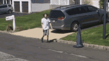 a man walking down a sidewalk in front of a van with a license plate that says ' sd ' on it