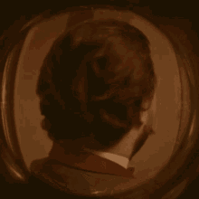 a man with a beard and bow tie is looking through a round window