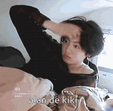 a woman laying on a bed with the words alan de kiki on the bottom right