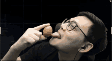 a man with glasses is eating an egg with his tongue hanging out