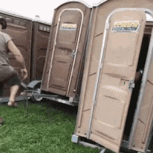 a man is standing next to a trailer with portable toilets attached to it and one of them is open