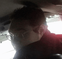 a man wearing glasses and a red shirt is sitting in the back seat of a car