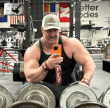 a man taking a selfie in a gym with a sign that says better bodies