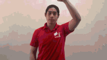 a man in a red shirt with a white flag on it is raising his arm