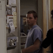 a man in scrubs is standing in front of a locker with a sign that says ' emergency room ' on it