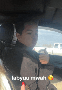 a man giving a thumbs up while sitting in a car with the words labyuu mwah below him