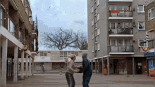 a man and woman are dancing in a courtyard in front of a building with a sign that says ' 10 ' on it