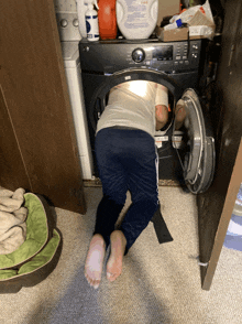 a person is looking into a washing machine with a bottle of detergent on top