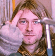 a close up of a man making a peace sign with his finger .