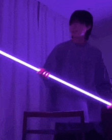 a man is holding a purple lightsaber in a dark room .