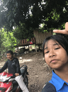 a girl in a blue shirt is sitting on a red motorcycle