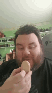 a man with a beard is eating a cookie in front of a shelf that has a triangle on it