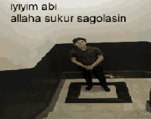 a man sits on a staircase with the words " iyiyim abi allaha sukur sagolasin " on the wall