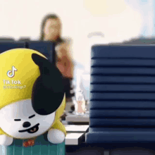 a stuffed animal is sitting on a desk in an office with a woman in the background .