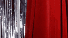 a close up of a red curtain behind a silver tinsel .