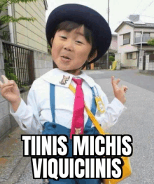 a little boy wearing a hat and tie says " tiinis michis viquiiinnis " .